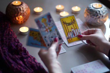 Tarot okuyucusu yanan mumların yanında tarot kartları topluyor..