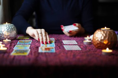 Tarot okuyucusu yanan mumların yanında tarot kartları topluyor..