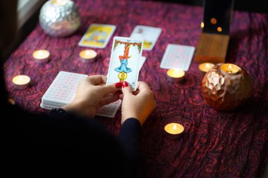 Tarot okuyucusu yanan mumların yanında tarot kartları topluyor..