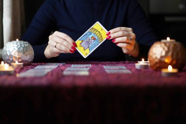 Tarot okuyucusu yanan mumların yanında tarot kartları topluyor..