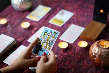 Tarot okuyucusu yanan mumların yanında tarot kartları topluyor..