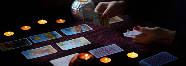 Tarot okuyucusu yanan mumların yanında tarot kartları topluyor.. — Stok fotoğraf