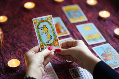 Tarot okuyucusu yanan mumların yanında tarot kartları topluyor..