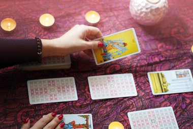 Tarot okuyucusu yanan mumların yanında tarot kartları topluyor..