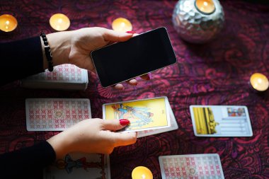 Tarot okuyucusu yanan mumların yanında tarot kartları topluyor..