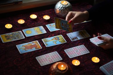 Tarot okuyucusu yanan mumların yanında tarot kartları topluyor..