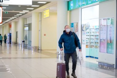 Avrupalı kızıl sakallı adam havaalanında koruyucu tıbbi maske takıyor.