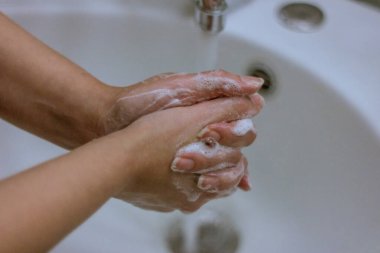 Koronavirüs salgınını önlemek için, bir kız ellerini sabun ve suyla yıkar, düzgün yıkama ve antiseptik kullanımı virüse karşı korur..