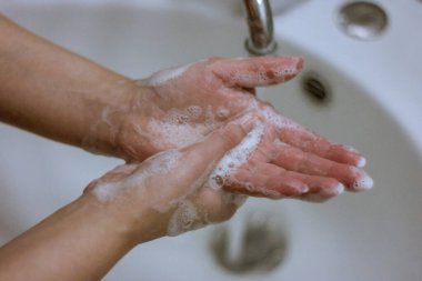 Koronavirüs salgınını önlemek için, bir kız ellerini sabun ve suyla yıkar, düzgün yıkama ve antiseptik kullanımı virüse karşı korur..