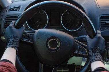 Koronovirüs salgını sırasında araba kullanmak. Lastik eldivenli bir kızın elleri direksiyonu tutar..