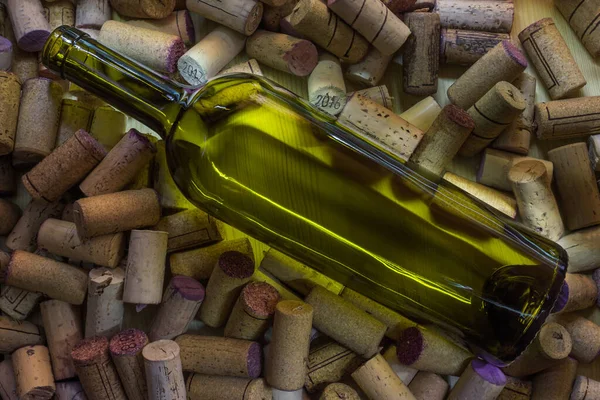 A bottle of wine without a label lies on a large number of wine corks. Cork tree and its texture for background