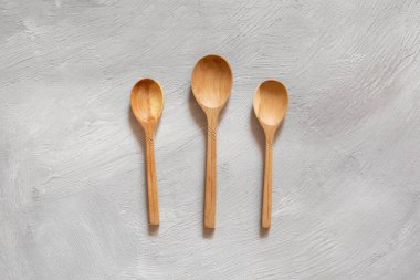 Gri arka planda tahtadan yapılmış tahta kaşıklar. Çevre dostu yemekler..