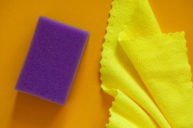 Temizlik ve yıkama kavramı. Sarı arka planı temizlemek için renkli süngerler ve sarı mikrofiber kumaş karışımı..