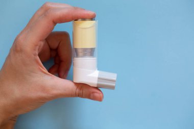 Mavi arka planda astım spreyi var. Astımın tedavisi..