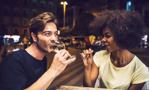 Casual interracial couple drinking wine during date