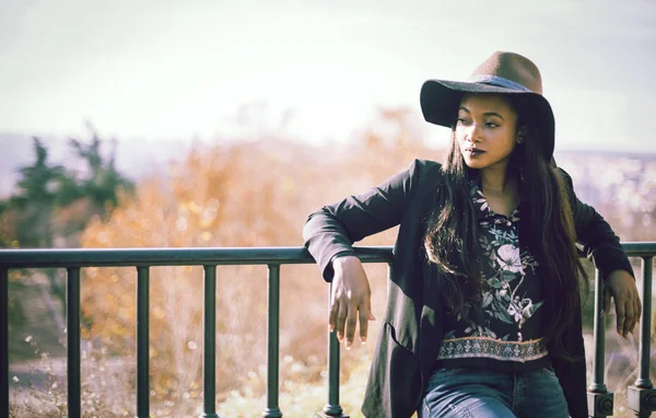 Portrait of black female leaning on fencing