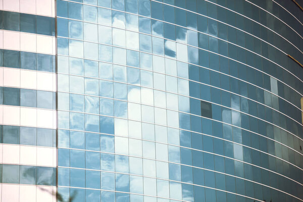 Cloudy sky mirrored in the windows of the office building. Vertical outdoors shot.