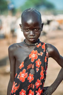 MUNDARI TRIBE, Güney Sudan, Afrika 'da Mundari Kabile Köyü' nde yaşarken el ele tutuşan ve kameraya bakan geleneksel giysili çocuk