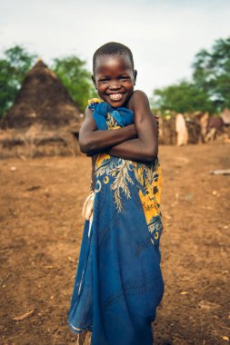 TOPOSA TRIBE, Güney Sudan, Afrika 'da Toposa Kabile Köyü' nde yaşarken kameraya gülümseyen ve kollarını kavuşturan mutlu çocuk.