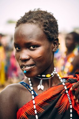 TOPOSA TRIBE, Güney Sudan, Afrika 'da Toposa Kabile Köyü' nde yaşarken piercing takan, kısa saçlı, gülümseyen ve kameraya bakan genç kadın