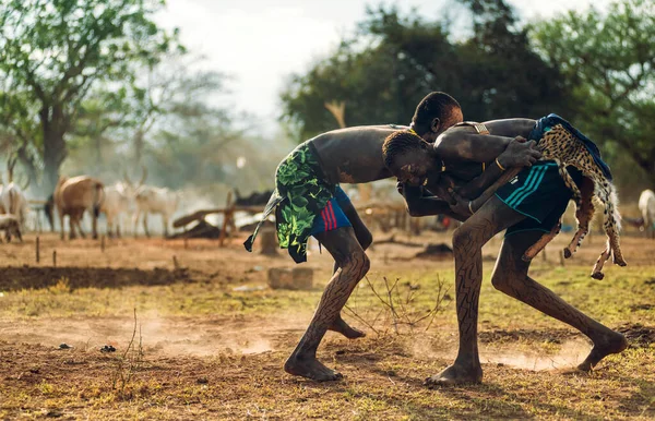MUNDARI TRIBE, ZUID SUDAN - 11 maart 2020: Jonge mannen lachen en worstelen op het veld bij vee van de Mundari-stam op zonnige dag in Zuid-Soedan, Afrika — Stockfoto
