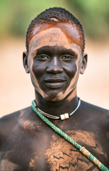 MUNDARI TRIBE, SOUTH SUDAN - Březen 11, 2020: Mladý muž s popelavě malovanou ozdobou na tváři, usmívající se a dívající se do kamery ve vesnici Mundari Tribe v Jižním Súdánu, Afrika — Stock fotografie