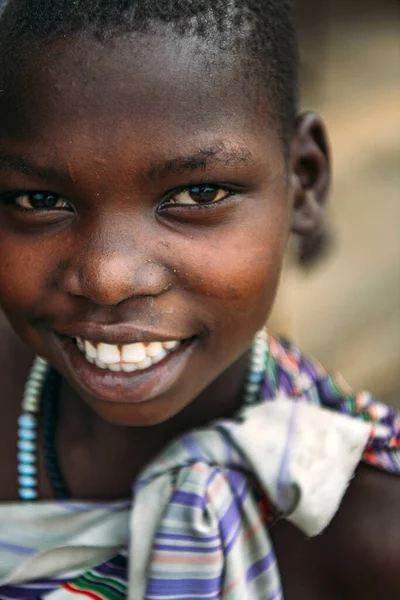 TOPOSA TRIBE, SOUTH SUDAN - MARCH 12, 2020: Girl in colorful garment with beads smiling and looking at camera in village of Toposa Tribe in South Sudan, Africa — Stock Photo, Image