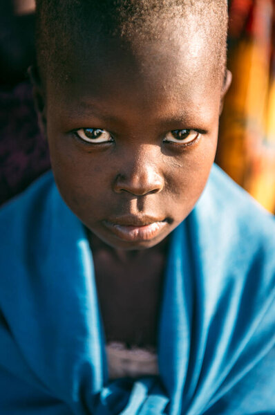 BOYA TRIBE, SOUTH SUDAN - 10 марта 2020 года: Ребенок, завернутый в голубую ткань, смотрит в камеру, когда живет в деревне племя Бойя в Южном Судане, Африка
