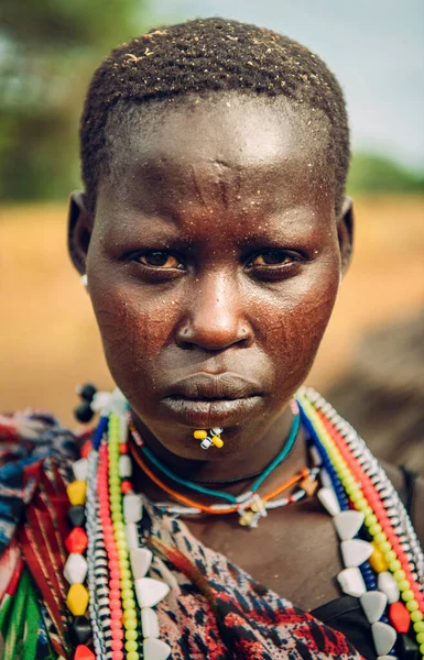 TOPOSA TRIBE, SUD SUDAN - 12 MARZO 2020: Donna della tribù Toposa indossa perline colorate tradizionali e piercing e guarda la fotocamera in Sud Sudan, Africa — Foto Stock