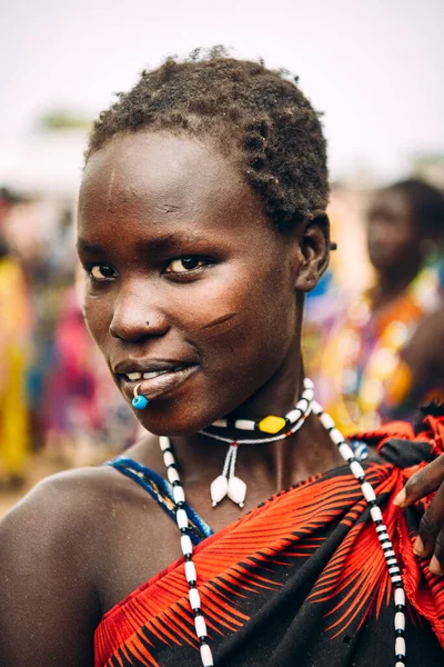 TOPOSA TRIBE, JIŽNÍ SUDAN - 12. března 2020: Mladá žena s pronikavými a krátkými vlasy, usmívající se a dívající se do kamery, zatímco žije ve vesnici Toposa Tribe v Jižním Súdánu, Afrika Royalty Free Stock Fotografie