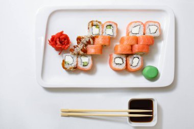 Suşi ruloları Philadelphia 'yı beyaz arka planda beyaz seramik bir tabağa koyuyor. Yatay fotoğraf. Japon yemeği..