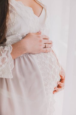 Güzel elbiseli hamile bir kadının koca göbeğine dokunuşu. Dikey fotoğraf. Kapatın. Annelik, hamilelik.,