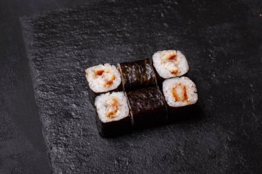 Siyah arka planda yılan balıklı maki suşi rulolarının yakın çekimi