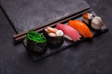 Siyah arkaplanda yemek çubukları olan sashimi suşisini kapat.