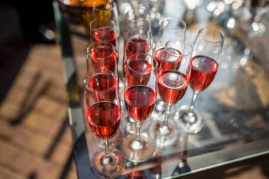 Güneş ışığının altındaki tepside şarap kadehleri. Kapat.