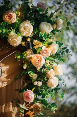 Düğün töreni için açık hava süslemeli alan. Güllerle süslenmiş ahşap bir kemer. Dikey fotoğraf.