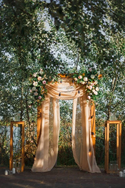 Im Freien dekorierter Bereich für die Hochzeitszeremonie mit einem mit Rosen geschmückten Holzbogen. — Stockfoto