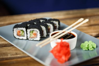 Somon, pirinç, nori, krema peyniri ve beyaz kremik tabakta suşi ruloları..