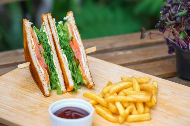 Somonlu sandviç, salata, sebze, marul, domates, soğan ve ahşap zemin üzerinde taze dilimlenmiş ekmek. Yatay fotoğraf. Kapat.