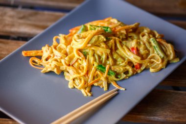 Gri seramik tabakta tavuk ve sebzeli Udon Kalın buğday eriştesi. Japon yemeği..