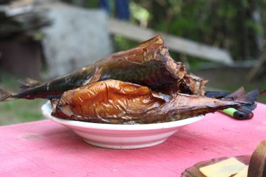 Tütsülenmiş uskumru tabaklar üzerinde pembe bir masa örtüsü üzerinde doğanın arka planında