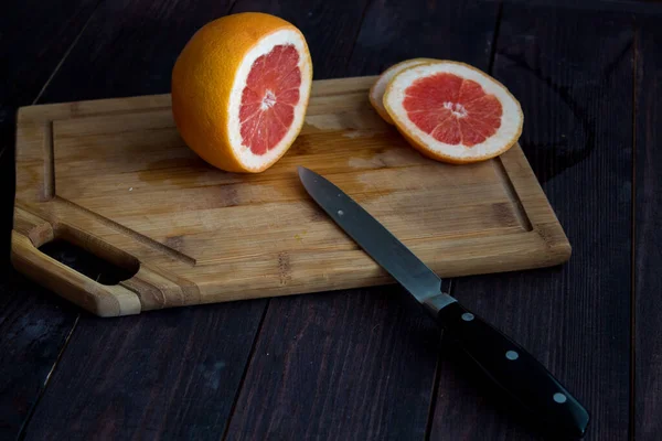 Greyfurtu ahşap bir masada ahşap bir tabakla kes. kırmızı greyfurt
