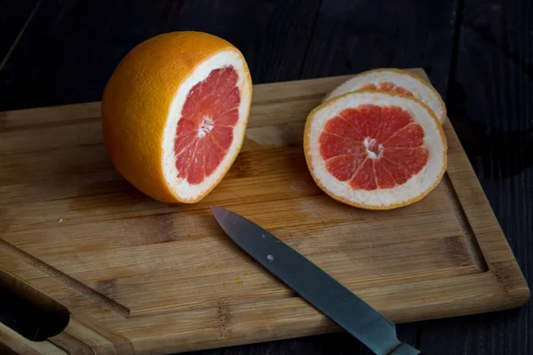 Greyfurtu ahşap bir masada ahşap bir tabakla kes. kırmızı greyfurt