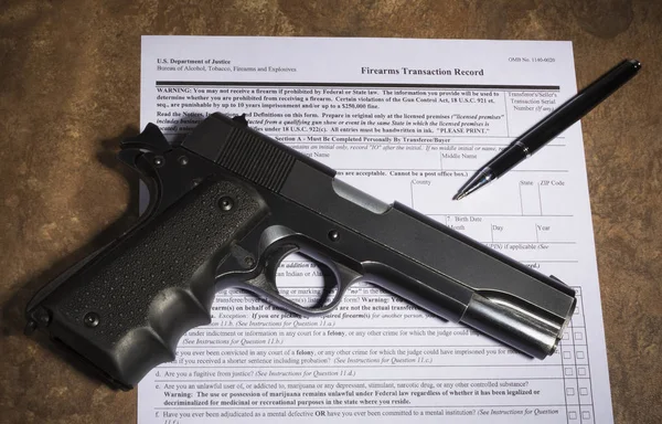 Used handgun and purchase paperwork on a tan counter — Stock Photo, Image