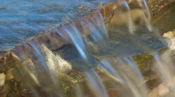 Kaskadowo, przepływającym przez niektóre skały — Zdjęcie stockowe