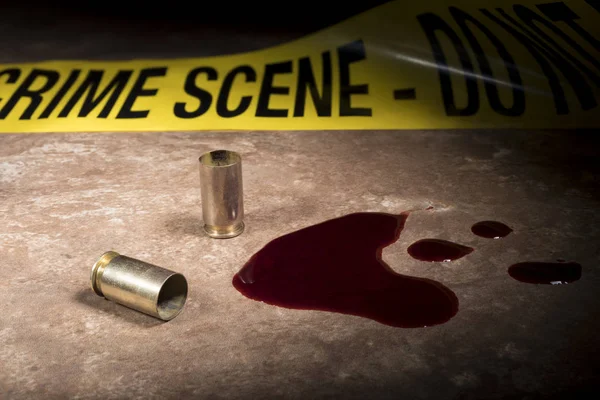 Scene of a crime with empty pistol brass and blood and police ta — Stock Photo, Image