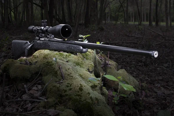 High powered rifle with a scope in a forest with room for text