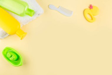 Spa ve banyo konsepti. Bebek banyosu. Lastik ördek, bez, sabun şişesi, şampuan, havlu ve sarı arka planda tarak..