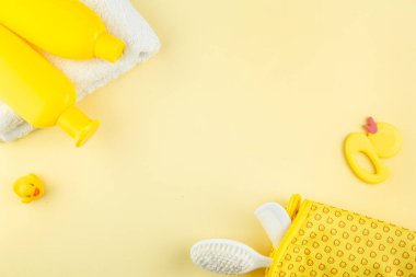 Spa ve banyo konsepti. Bebek banyosu. Lastik ördek, bez, sabun şişesi, şampuan, havlu ve sarı arka planda tarak..