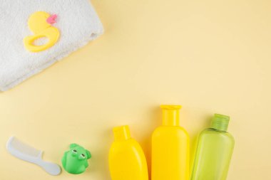 Spa ve banyo konsepti. Bebek banyosu. Lastik ördek, bez, sabun şişesi, şampuan, havlu ve sarı arka planda tarak..